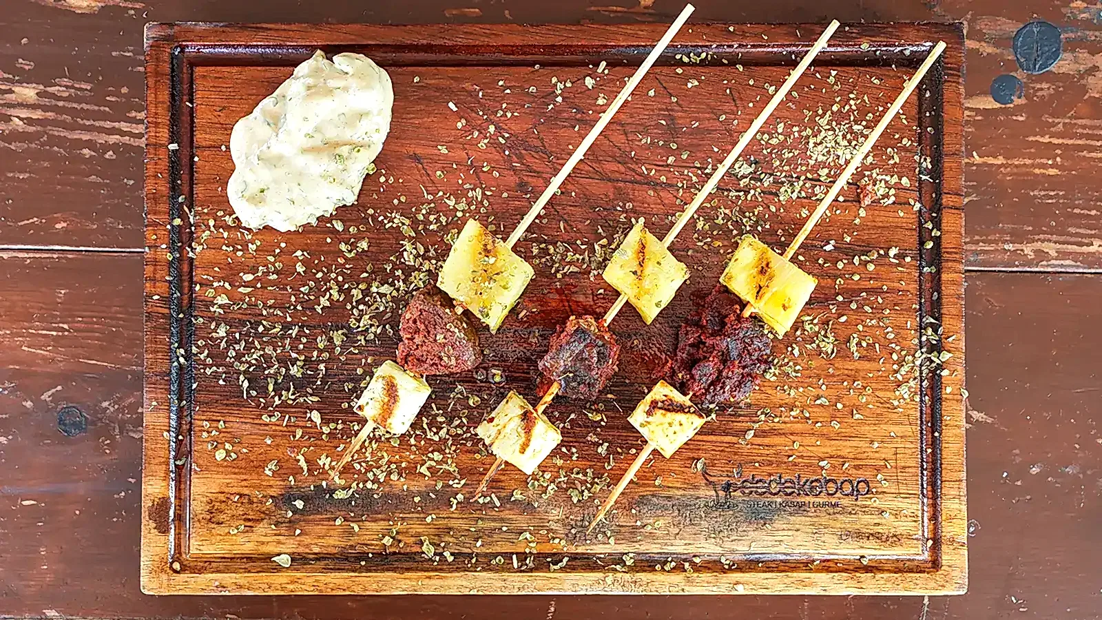 Özel Aşk Üçgeni, köz ateşinde pişirilmiş sucuk, ızgara peynir ve ananas dilimlerinden oluşan şiş sunumu, yanında özel sos ile – Bakı Dede Kebap Steak Burger Tatlı Kasap