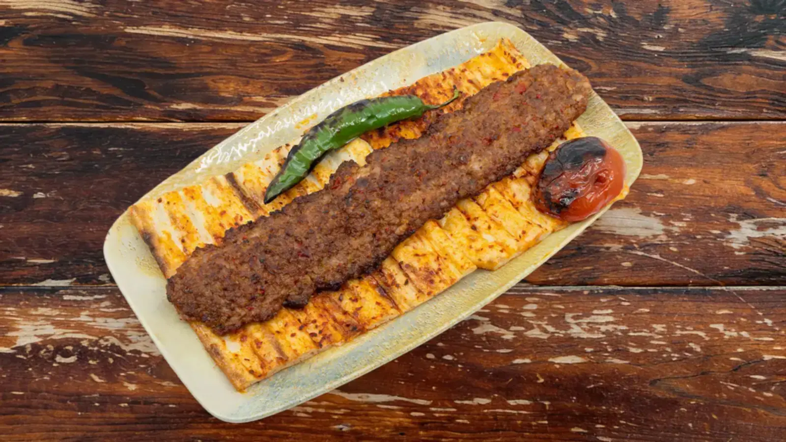 Kömür ateşinde közde pişirilmiş acılı Bakı Kebap şiş, yanında közlenmiş domates, biber ve sıcak pide ile porsiyon sunum – Bakı Dede Kebap Steak Burger Tatlı Kasap